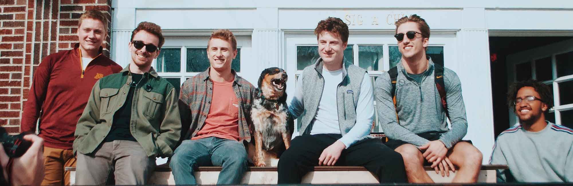 students sit on the wall in front of the student club and take a picture of themselves